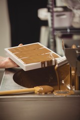 Worker filling mould with melted chocolate