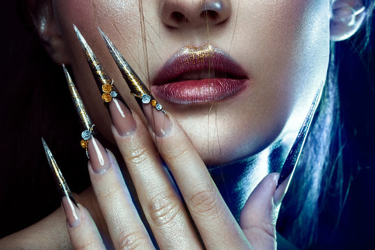 Fototapeta Beautiful girl with creative golden and silver glitter make-up and long nails art. The beauty of the face. Photos shot in studio