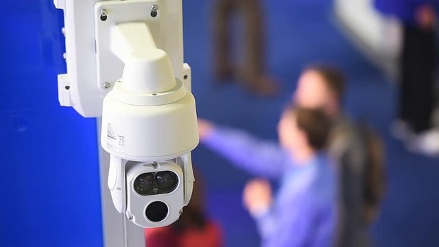Surveillance camera inside a company with people in the background