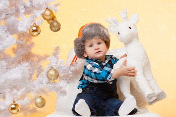little boy in a cap near Christmas tree enjoys