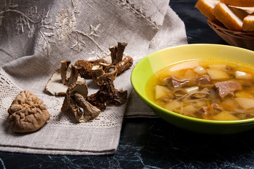 Mushroom soup in green plate, dried wild mushrooms and basket of