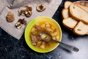 Mushroom soup in green plate with metal spoon, dried wild mushro