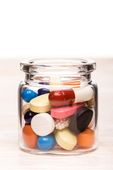 Colored pills in transparent glass container