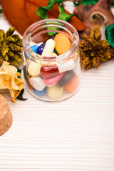 Various pills and capsules in glass container with green