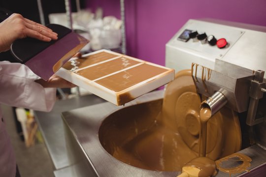 Worker filling mold with melted chocolate