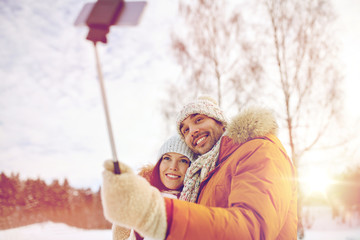 happy couple taking selfie by smartphone in winter