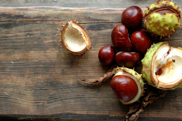 Several ripe chestnuts on a wooden background.