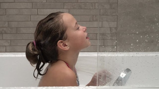 Little girl playing with water in the bathroom, taking shower