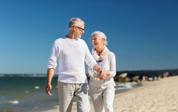 happy senior couple holding hands on summer beach - Powered by Adobe