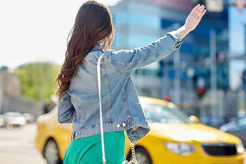 young woman or girl catching taxi on city street
