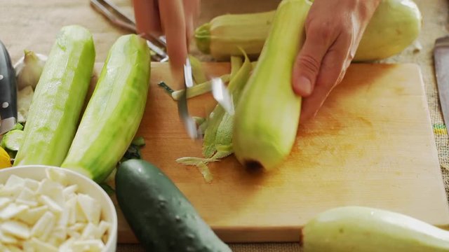 HD 1080 static: chef peeling zucchini using peeler hand tool; close up;