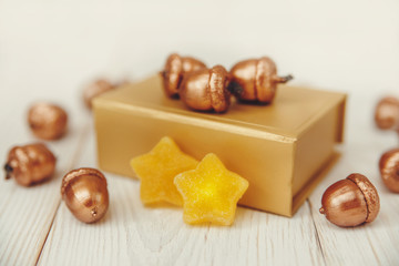 Christmas composition.Golden present box and golden acorns.White wooden table,jujube stars.Selective focus