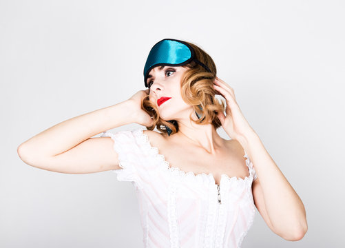 beautiful young woman in pink dress and points for sleep, standing, posing. sleeping eye covering mask