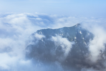 Picturesque view of a layer of white clouds below the mountain peaks in the Bucegi Mountains from the Carpathians in Romania. Mountain scenic landscape above the clouds.