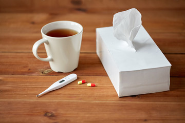 cup of tea, paper wipes and thermometer with pills
