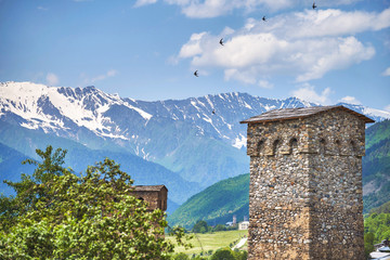 Ancient Svan tower and the flying birds in Mestia. Svaneti, Georgia