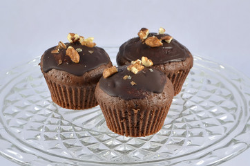 three chocolate brown muffins with nuts on glass plate photography