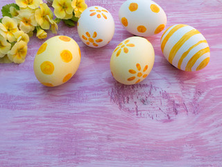 Easter eggs and primrose flowers composition on the violet woode
