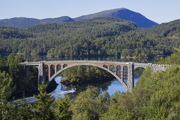 Fototapeta na wymiar Old bridge to the wooded island in the middle of the bay, Norway