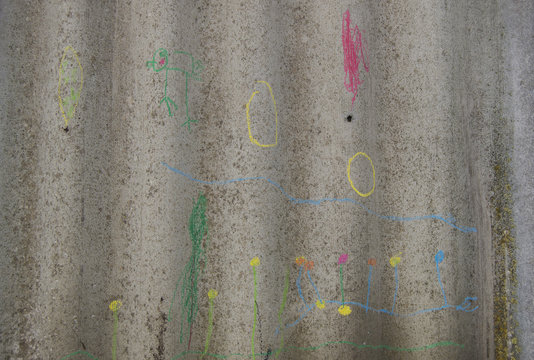 children's drawings in chalk on gray fence