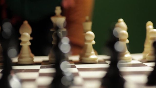 Panning shot of a chess board with a hand moving the white horse.