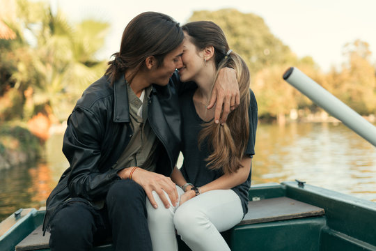 Young couple kissing in boat in river.