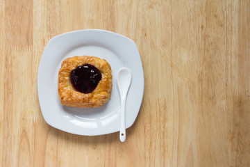 Danish blueberry pie with spoon in white plate on wooden table