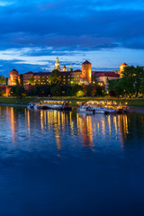 Wawel hill with castle and reflections in Wisla river in Krakow at night, Poland