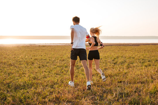 Back view of young fitness man and woman doing jogging