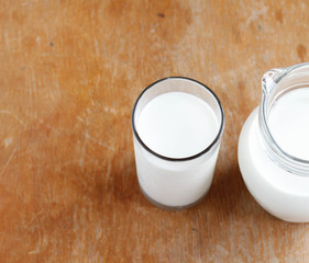 Natural whole milk in a jug and a glass on  the old wooden background