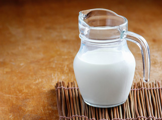 Natural whole milk in a jug and a glass on  the old wooden background
