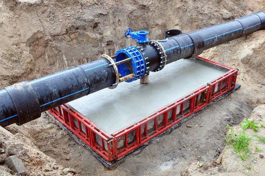The process of installation of the distribution unit heating network. Frame for connecting pipes on a concrete support in the trench of sand.