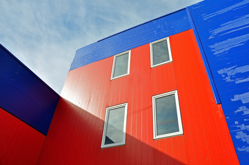 Industrial building of red and blue sandwich panels with windows lit by the sun. Look up. 