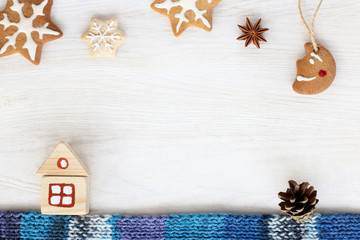 festive Christmas tale/ idea of a wooden house with figured cookies, cones and scarf on a light background 