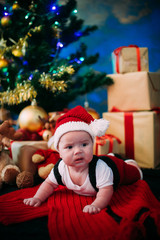 Obraz na płótnie Canvas fairy-tale portrait of Christmas cute little baby wearing like santa claus at the new year background under tree