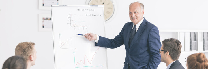 Man making a presentation close to the board with charts