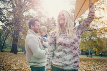 Dad, mom and son flying a kite in nature 