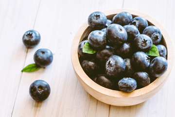 Blueberries in wooden bowl on wooden background