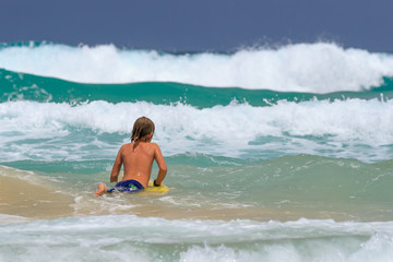 Young Surfer with surfboard going to the sea at surf spot.