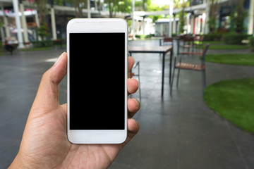 Man's hand shows mobile smartphone in vertical position, blurred