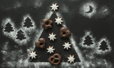 Christmas cookies on the Christmas tree made of flour on the black background.