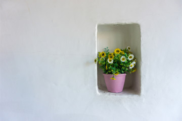 Artificial flower in pink pot on white cement wall textured