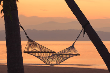 Fabric hammock against mountain and sea at sunrise background. Soft focus