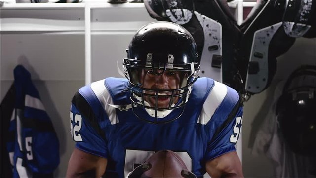 A football player in full protective gear standing in front of his locker