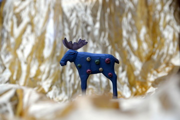 Weihnachtselch, aus Holz geschnitzter blauer Elch mit bunten Schellen vor goldenem Hintergrund