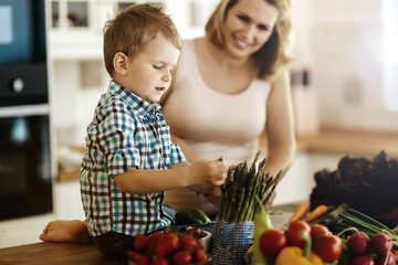 Pregnant woman preparing meal with son