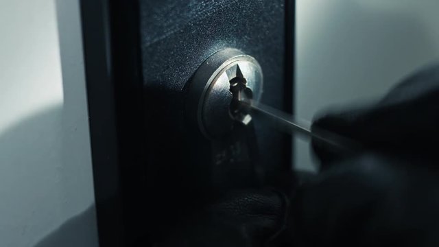 Close up shot of a burglar picking a lock from an office door