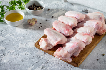 Raw chicken wings on a concrete table with spices