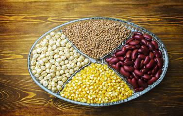 Fresh organic grains in glass plate placed on wooden background. Top view.