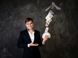 Illusionist man with fountain of cards on a dark background.